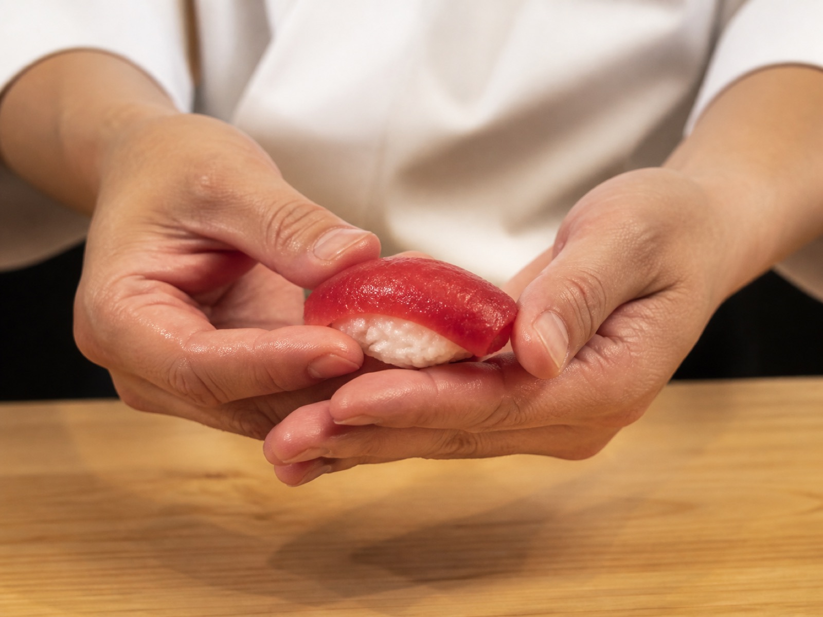 Tay đầu bếp nắm nigiri cá ngừ tại quầy Ginrei Omakase